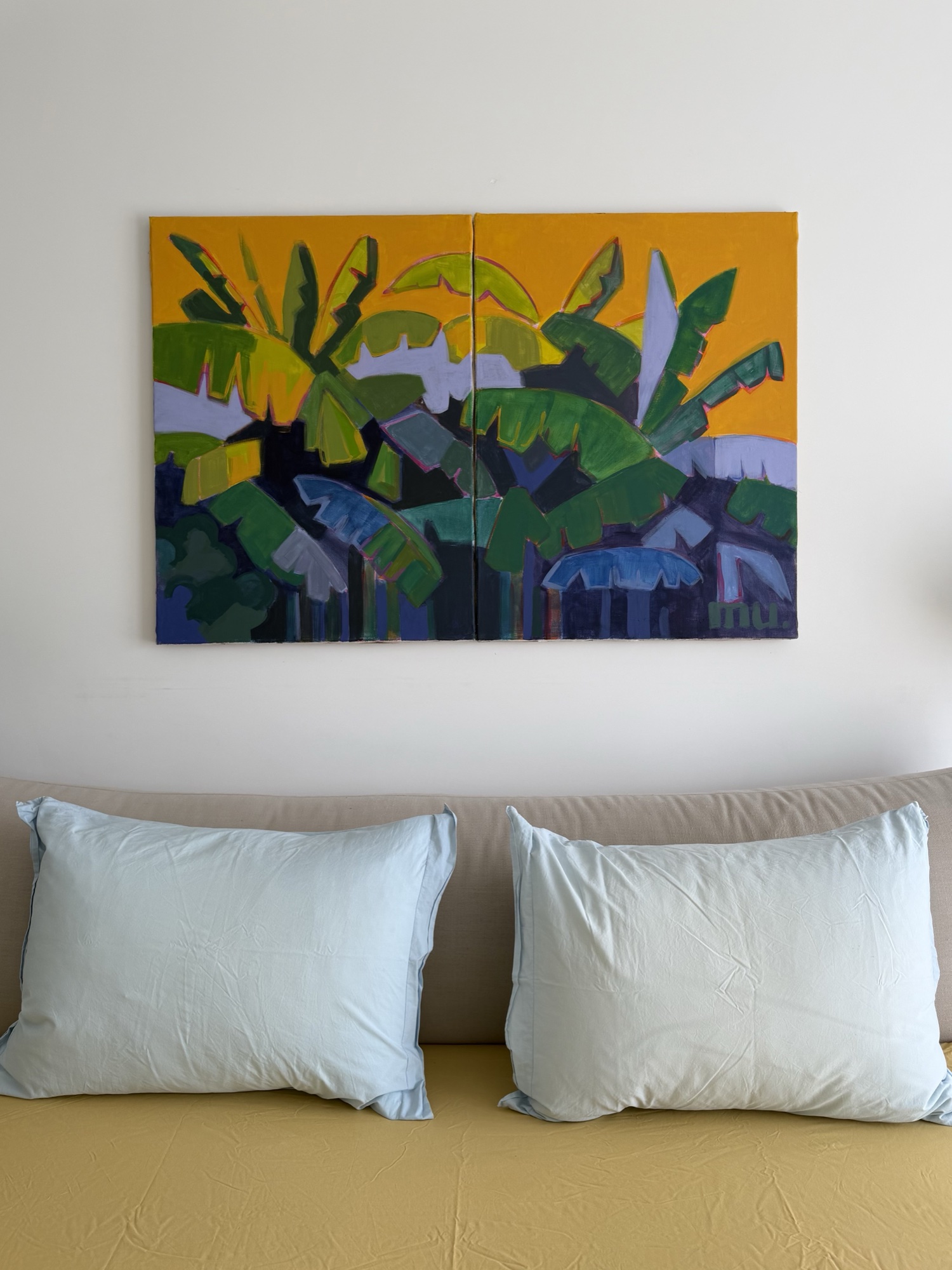 Green tropical foliage against a golden sky, displayed above a sofa